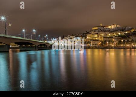 Brücke auf dem Meer in Coimbra mit den Lichtern reflektierend Auf dem Wasser während der Nacht in Portugal Stockfoto