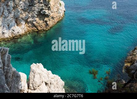 Die Sommersonne lädt das klare, klare, blaue und türkisfarbene Wasser zum Leuchten in einer Bucht der Insel Skopelos ein und Sie wollen sich zur Erfrischung einlassen. Stockfoto