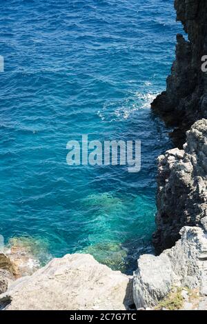 Die Sommersonne lädt das klare, klare, blaue und türkisfarbene Wasser zum Leuchten in einer Bucht der Insel Skopelos ein und Sie wollen sich zur Erfrischung einlassen. Stockfoto