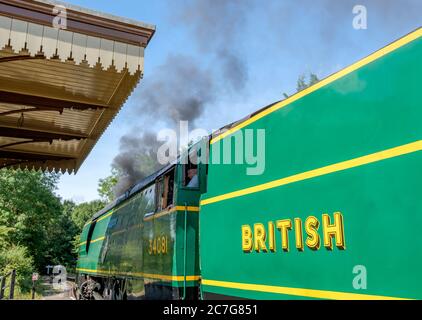 Ansicht einer restaurierten, alten britischen Dampflokomotive mit den beiden Triebwerksfahrern in der Kabine, die die Lok in eine Station umkehren wollen. Stockfoto