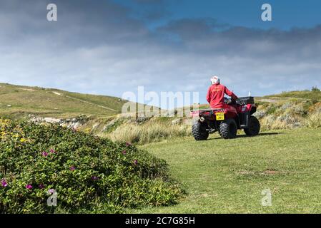 Ein RNLI Rettungsschwimmer auf einem Quad-Bike entlang des Küstenweges bei Fistral in Newquay in Cornwall. Stockfoto