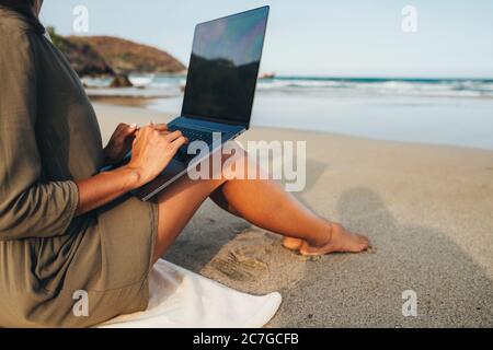 Freiberufler arbeitet am Strand am Meer bei Sonnenuntergang, arbeitet in einem nicht-Büro. Das Konzept der Fernarbeit. Arbeit im Internet, Kommunikation thr Stockfoto