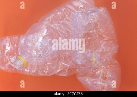Kunststoff zerknittert Flasche vor orangefarbenem Hintergrund, Umweltverschmutzung und Recycling-Konzept Stockfoto