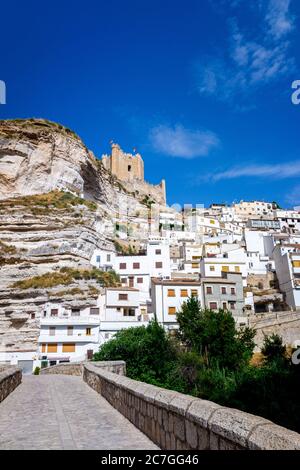 Blick auf die spanische Touristenstadt Alcala del Jucar, mit ihrem Schloss und weißen Häusern von der mittelalterlichen Brücke. Stockfoto