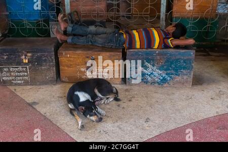 Ein Hund und ein Mann schlafen aufgrund Corona-Virus, es gibt keine Arbeit kein Essen. Ich habe dieses Bild von einem Bahnhof, der Kamalapur Eisenbahn s genannt wird, aufgenommen Stockfoto