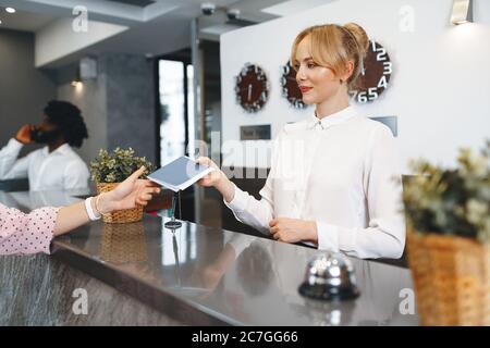 Die Dame an der Rezeption nimmt den Pass der Gäste mit zum Einchecken Stockfoto