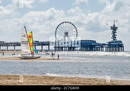 Scheveningen, Niederlande, 11. Juli 2020: Zwei Katamarane am Strand in der Nähe der Wasserlinie mit im Hintergrund der Pier mit Turm und Ferris whe Stockfoto