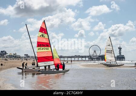 Scheveningen, Niederlande, 11. Juli 2020: Vier Katamarane in den Untiefen nahe am Strand mit im Hintergrund der Pier und Promenade Bereich Stockfoto