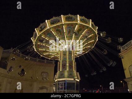 Low-Angle-Aufnahme eines Kettenkarussells bei Nacht in Action mit beweglichen Schaukeln Stockfoto