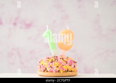 Ein kleiner, farbenfrohes Cupcake mit der Nummer dreizehn geformter Kerze für die Geburtstagsfeier Stockfoto