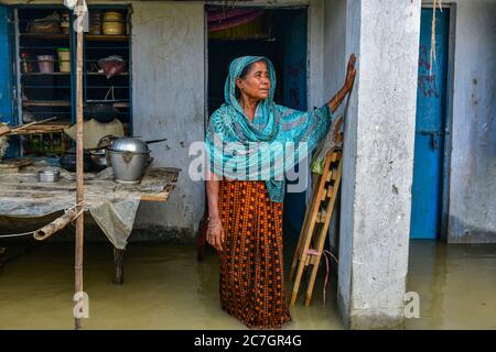 Bogura, Bangladesch. Juli 2020. Eine Frau steht vor ihrem überfluteten Haus in Bogura.ein Drittel von Bangladesch ist unter Wasser, nachdem schwere Regenfälle die Nation getroffen haben. Mindestens 1.5 Millionen Menschen sind betroffen, Häuser und Straßen in Dörfern überschwemmt. Beamte des Hochwasserprognosen- und Warnzentrums (FFWC) haben berichtet, dass die Hochwassersituation in 15 nördlichen und zentralen Bezirken auf den Anstieg der Wasserstände der Hauptflüsse zurückzuführen ist, einschließlich der Brahmaputra, Jamuna, Padma, Teesta und Dharla. Kredit: SOPA Images Limited/Alamy Live Nachrichten Stockfoto