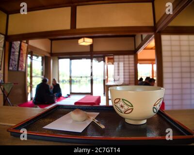 Weiße Tasse mit Designs auf einem schwarzen Tablett in einem Restaurant mit verschwommenem Hintergrund Stockfoto