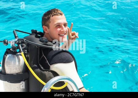 Taucher bereitet sich auf das Tauchen in blaues Wasser vom Boot aus. Unterwasserausrüstung. Stockfoto