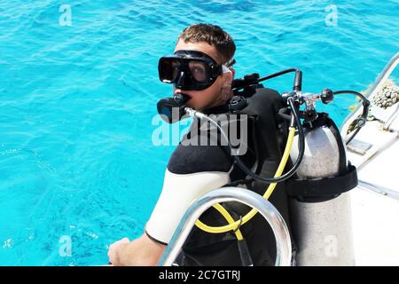 Taucher bereitet sich auf das Tauchen in blaues Wasser vom Boot aus. Unterwasserausrüstung. Stockfoto