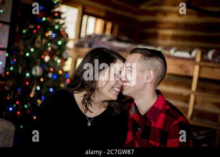 Glückliches Paar sitzt in einem Holzhaus in der Nähe der Weihnachten Baum Stockfoto