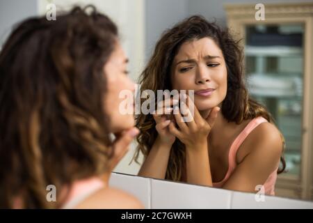 Schöne Frau quetscht Pickel im Badezimmer. Stockfoto