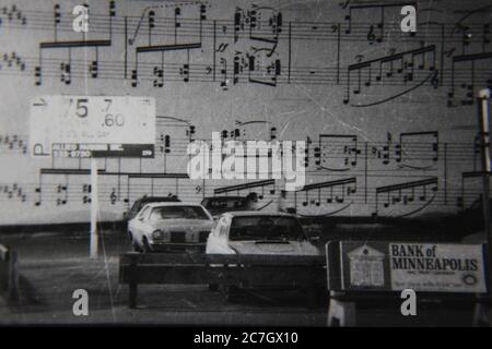 Feine 70er Jahre Vintage schwarz-weiß Lifestyle Fotografie eines Parkplatzes mit Noten auf der Gebäudewand gemalt. Stockfoto