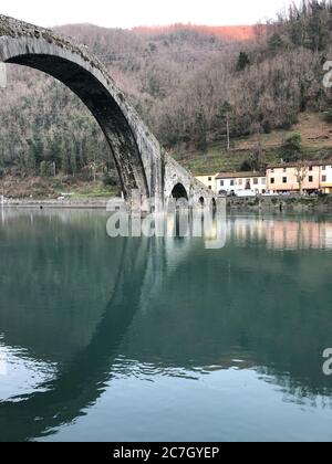 Devil Bridge umgeben von Hügeln mit viel Grün und Gebäuden In Borgo a Mozzano in Italien Stockfoto