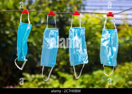 Selektive Fokussierung von Gesichtsmasken, die nach dem Waschen an einem Draht hängen. Stockfoto