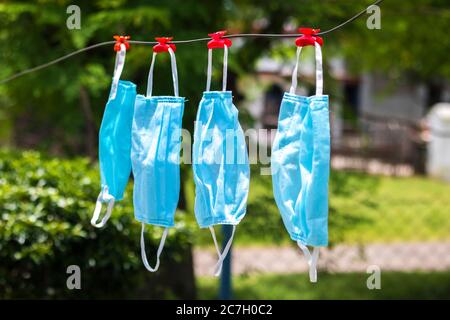 Selektive Fokussierung von Gesichtsmasken, die nach dem Waschen an einem Draht hängen. Stockfoto