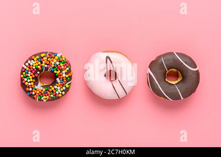 Klassische Schokolade, Erdbeere, mit bunten Streuseln Donut isoliert auf rosa Hintergrund Flach lat Lay Top View Knolling ungesund und lecker Stockfoto