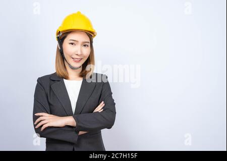 Porträt der jungen asiatischen Geschäftsfrau trägt gelben Schutzhelm in formellen Anzug lächelnd Blick auf die Kamera, im Studio aufgenommen Stockfoto