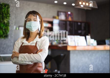 Neu normales Startup Kleinunternehmen Porträt der asiatischen Frau Barista trägt Schutzmaske stehen in ihrem Café während soziale Distanzierung Stockfoto