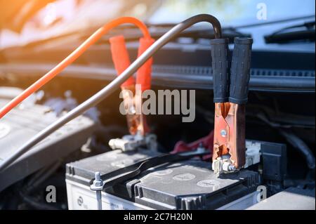 Schließen Sie die Überbrückungskabel der Batterie an die Autobatterie an, um die leere Batterie aufzuladen Stockfoto