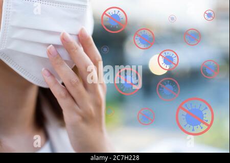 Medical und Stop Coronavirus oder Covid-19 Konzept, junge Frau trägt chirurgische Maske mit Virus Symbol umgibt Körper in der Öffentlichkeit Stockfoto