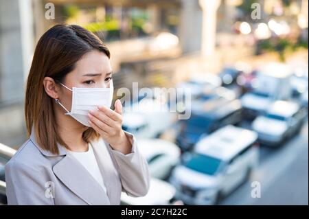 Junge Geschäftsfrau trägt chirurgische Maske und hugen beim Gehen in der Öffentlichkeit in Coronavirus oder COVID-19 Verbreitung Situation Stockfoto