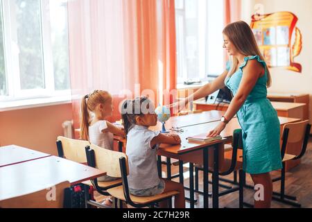 Geografie-Lehrerin zeigt zwei Schülerinnen auf einer Welt, Einzelunterricht, Wahlfach Stockfoto