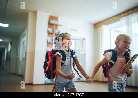 Zwei Schülerinnen, die sich die Hände halten, gehen den Schulkorridor entlang Stockfoto