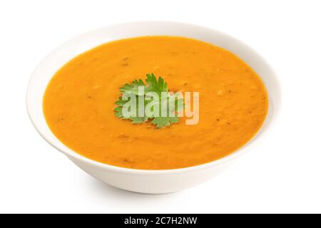 Karotten- und Koriandersuppe mit frischem Koriander garnieren in einer weißen Keramikschale, die auf Weiß isoliert ist. Hoher Winkel. Stockfoto