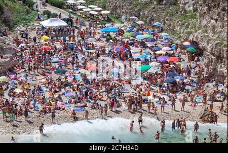 Polignano a Mare, Italien - 15. August 2014: Menschen entspannen und schwimmen am schönen Strand Lama Monachile. Weiße Kiesbucht zwischen Felswänden und Fledermaus Stockfoto