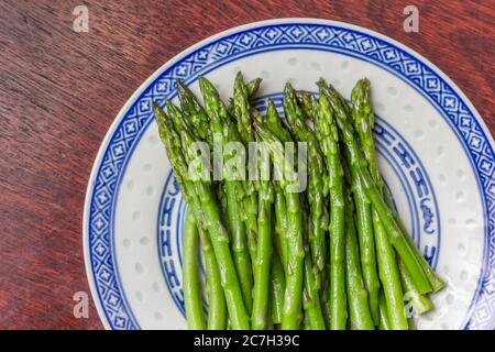 Grüner Spargel auf einem weißen Teller serviert Stockfoto
