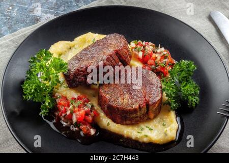 Rindermedaillons mit Tomatensalsa und Rahm Polenta Stockfoto