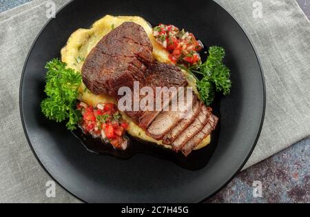 Rindermedaillons mit Tomatensalsa und Rahm Polenta Stockfoto