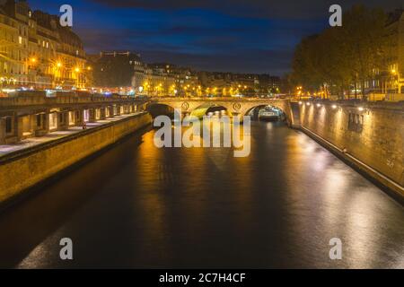 Kanal mit einer kleinen Bogenbrücke darauf umgeben von Gebäude und Lichter in der Nacht in Frankreich Stockfoto