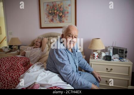 Ein älteres Paar in den 80ern saß auf dem Bett in ihrem Schlafanzug, bevor es morgens aufstand, England, Vereinigtes Königreich Stockfoto