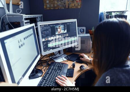 Mädchen verarbeitet Video auf Computer mit zwei Monitoren in der Seitenansicht. Computer-Arbeitskonzept. Lipik Stock Media Office. Mai 2019. Kiew, Ukraine Stockfoto