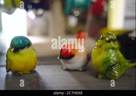 Nahaufnahme von bunten Vogelfiguren auf einem Holztisch darunter Die Lichter mit einem verschwommenen Hintergrund Stockfoto