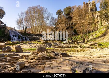 Europa, Spanien, Katalonien, Provinz Gerona, La Garrotxa, Sant Joan les Fonts, Blick auf den Wasserfall Salt del Molí Fondo und die Kirche in Sant Joan les Fonts Stockfoto