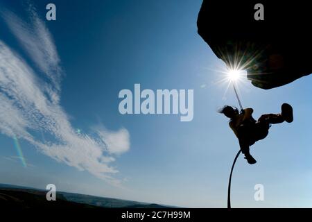 Frau, die von der Klippe bei Windgather Rocks in the Peak abseilt Bezirk Stockfoto