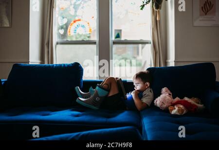 Vorschulalter Junge auf der Couch liegend beobachten Tablette auf regnerisch Tag Stockfoto