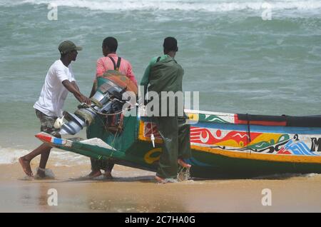 Handwerkliche Fischer schieben Pirogen aus dem Wasser in Lompoul, Senegal Stockfoto