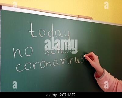 Mädchen Hand schreibt auf Tafel Inschrift heute keine Schule Coronavirus. Warnschild für Coronavirus im Klassenzimmer. Schulabsage an Coronavirus Pa Stockfoto