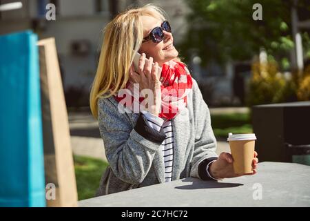 Lächelnde blonde Frau in Sonnenbrille, die die Sonne anschaut Stockfoto