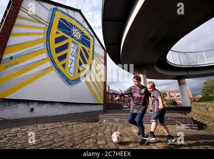 Die Fans von Leeds United Tyler und Harrison spielen Fußball vor einem Wandgemälde von Leeds United, das an den Häusern im Tilbury Mount in Holbeck gemalt ist, während Huddersfield Town West Bromwich Albion in einem Spiel, das ihre Beförderung zur Premier League besiegeln könnte, in die Hand nimmt. Stockfoto