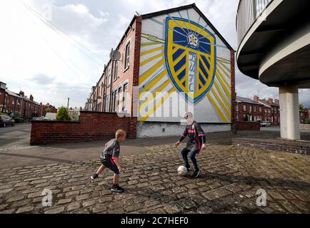 Die Fans von Leeds United Tyler und Harrison spielen Fußball vor einem Wandgemälde von Leeds United, das an den Häusern im Tilbury Mount in Holbeck gemalt ist, während Huddersfield Town West Bromwich Albion in einem Spiel, das ihre Beförderung zur Premier League besiegeln könnte, in die Hand nimmt. Stockfoto