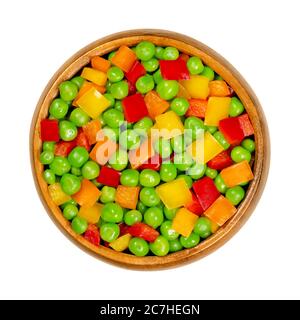 Grüne Erbsen und Paprika in Würfel geschnitten in Holzschüssel. Gemischtes Gemüse. Samen von Hülse Früchte Pisum sativum und schneiden gelbe, orange und rote Paprika. Stockfoto